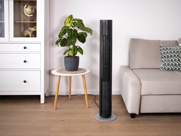 Bild vom Turmventilator Peter in Schwarz neben einem Sofa